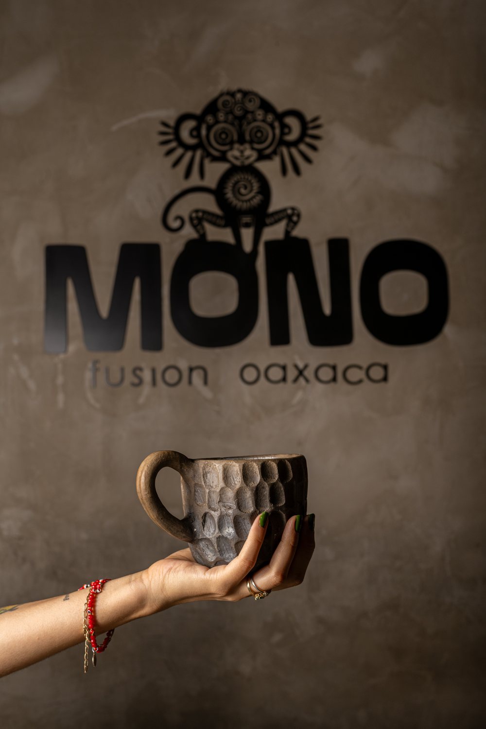 Taza de barro oaxaqueña frente al logo de MONO fusión oaxaca